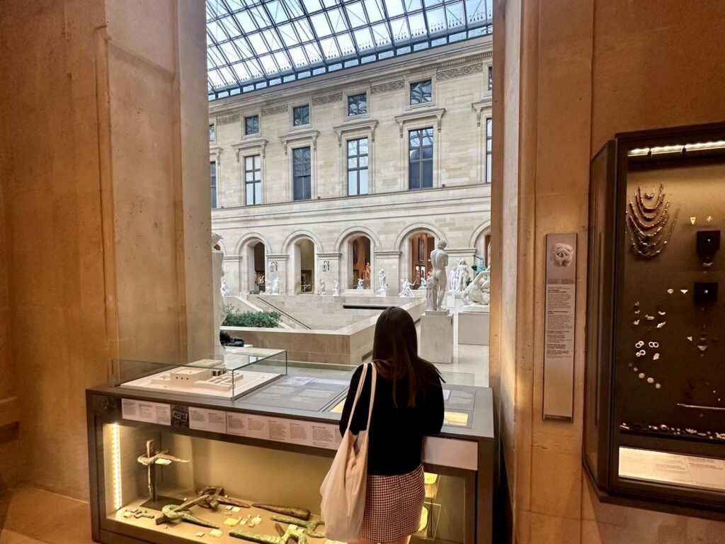 Woman looks out at view within the Louvre Museum practicing mindful travel