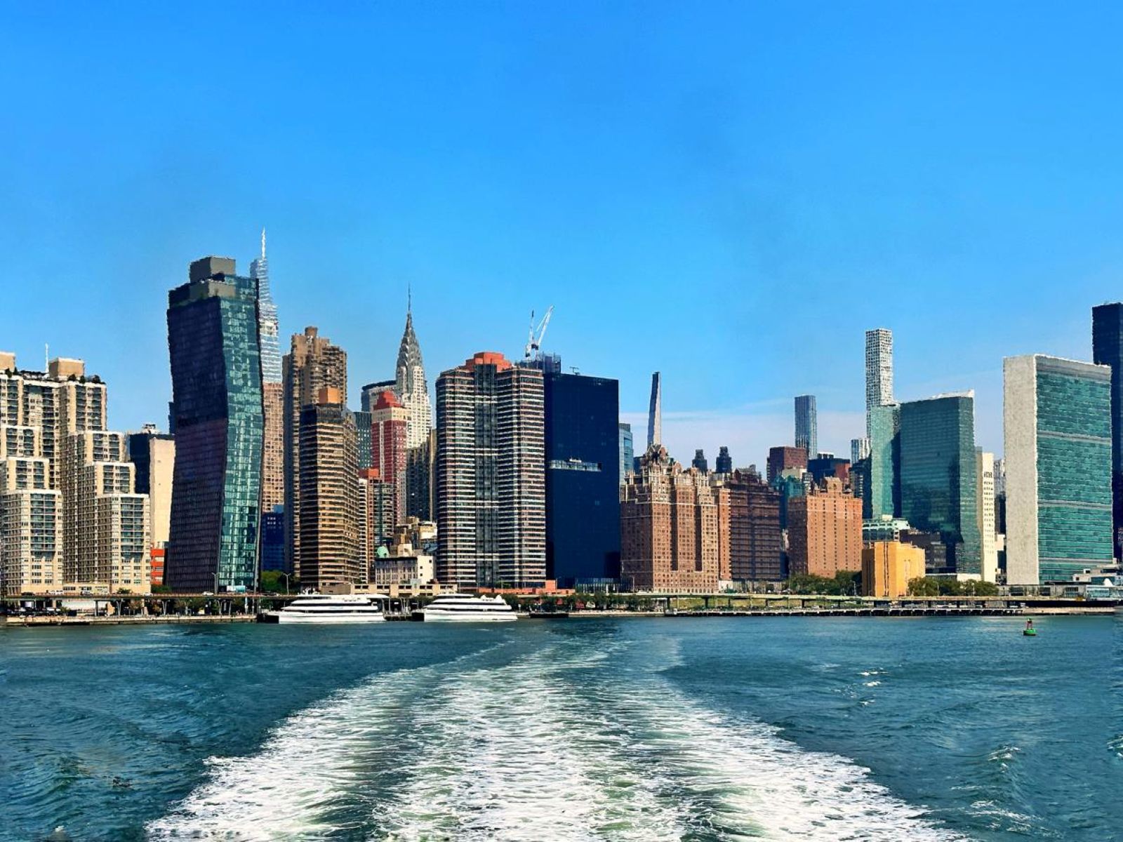 View of New York City skyline from the back of a New York Ferry on a sunny day