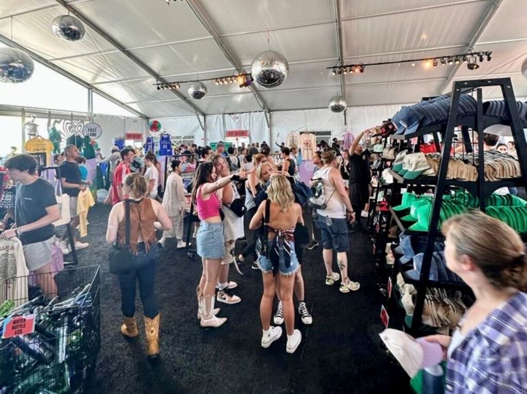 Inside a merch tent at a festival, poeple choosing what to buy