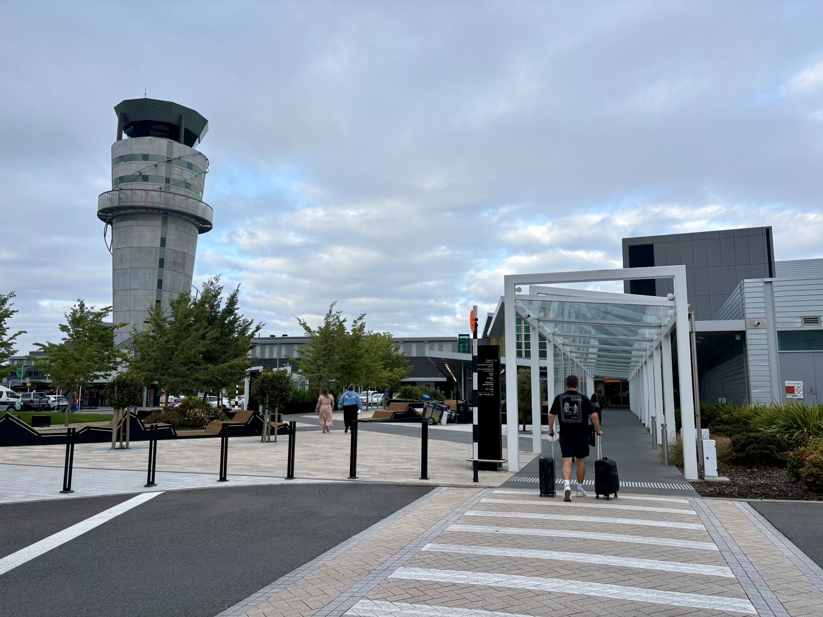 Man walking into airport wheeling two suitcases alongside him
