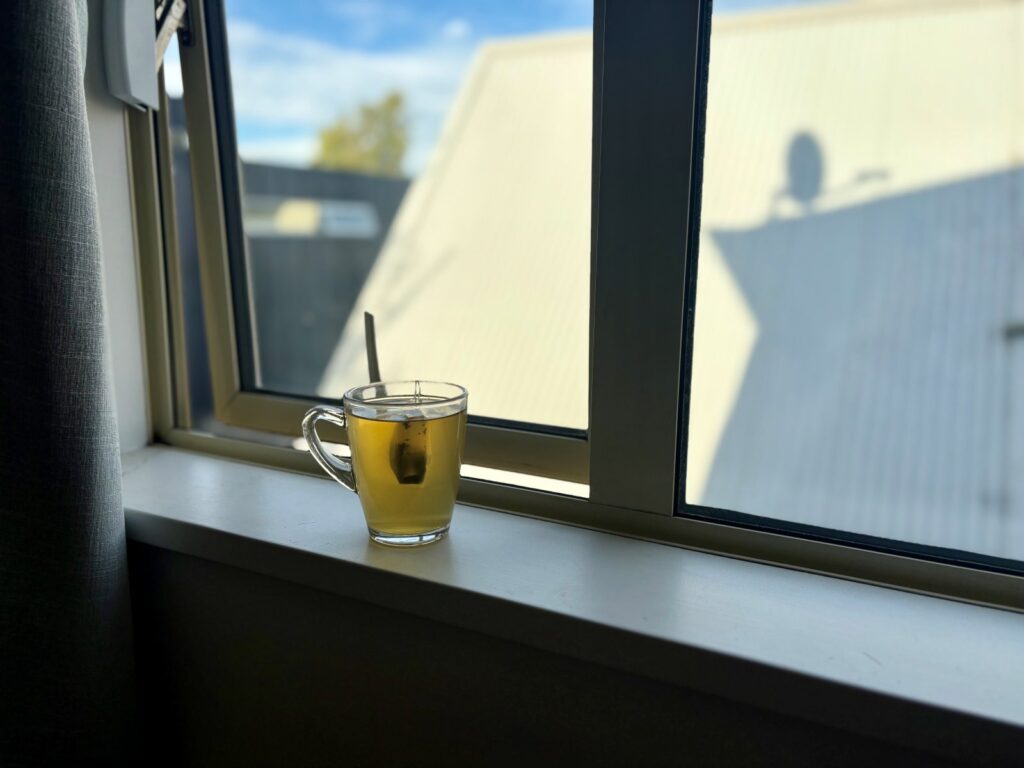 A morning cup of green tea sitting on a windowsill as part of a grounding practice for travelling