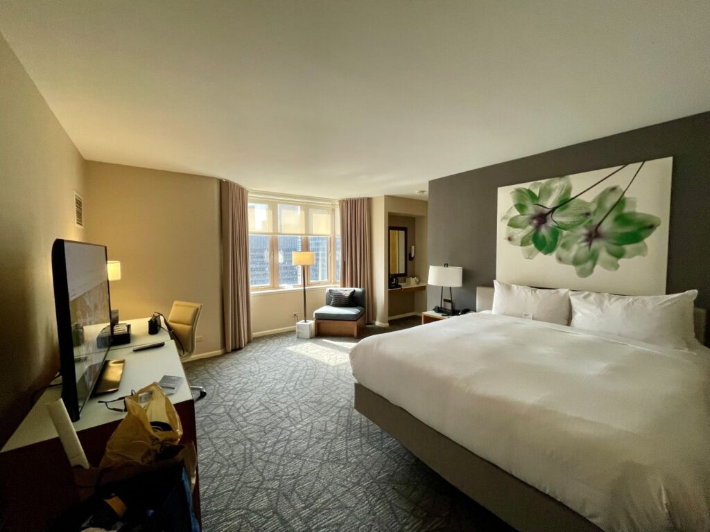 A hotel bed freshly made in a large hotel room