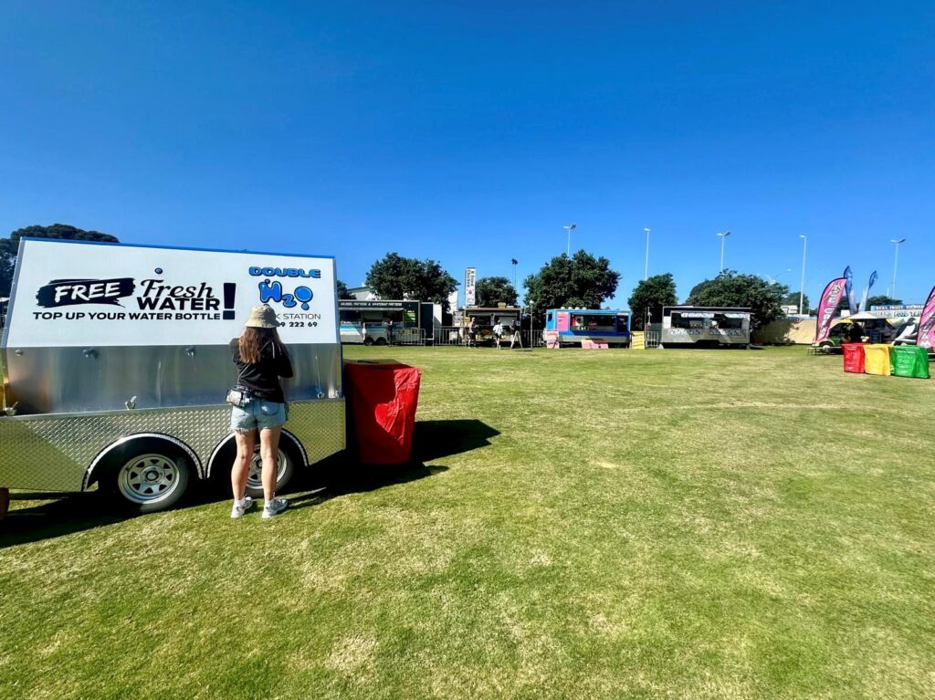 Person filling water bottle at festival, involving forward planning to alleviate festival financial anxiety