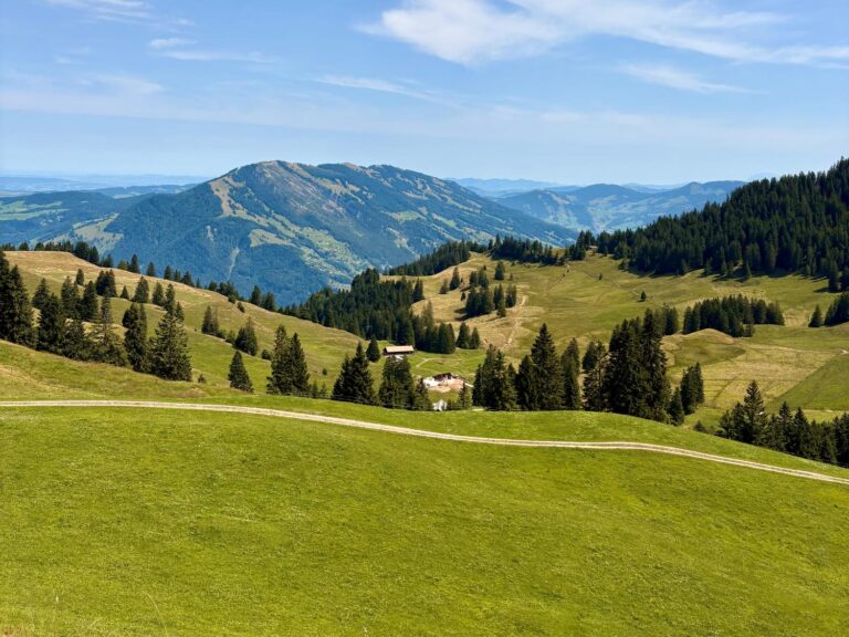 A hill in Switzerland with green hills and mountains in the background