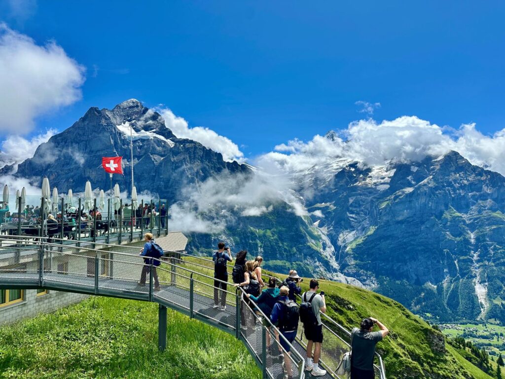 A hike in Switerland overlooking mountains with bright green grass below