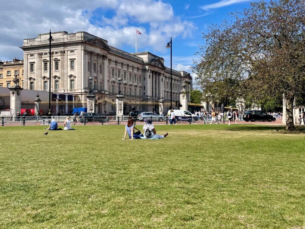 People sit on a lawnin London reaping the benefits of green spaces in travel