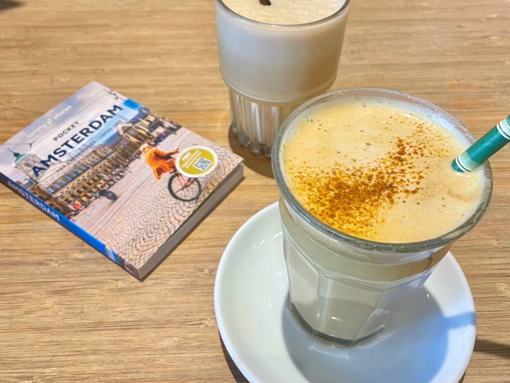 A Lonely Planet travel guide book sits on a cafe table by two hot drinks