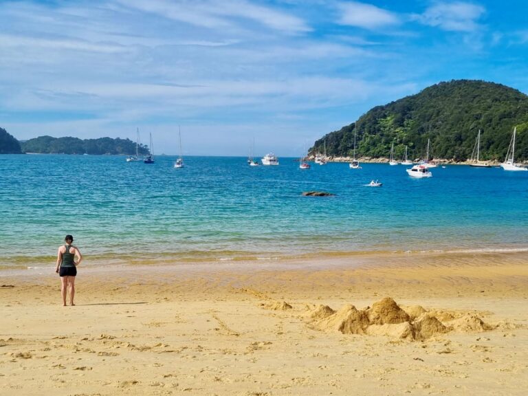 Woman looks over the ocean at a beach while practicing travel without social media use