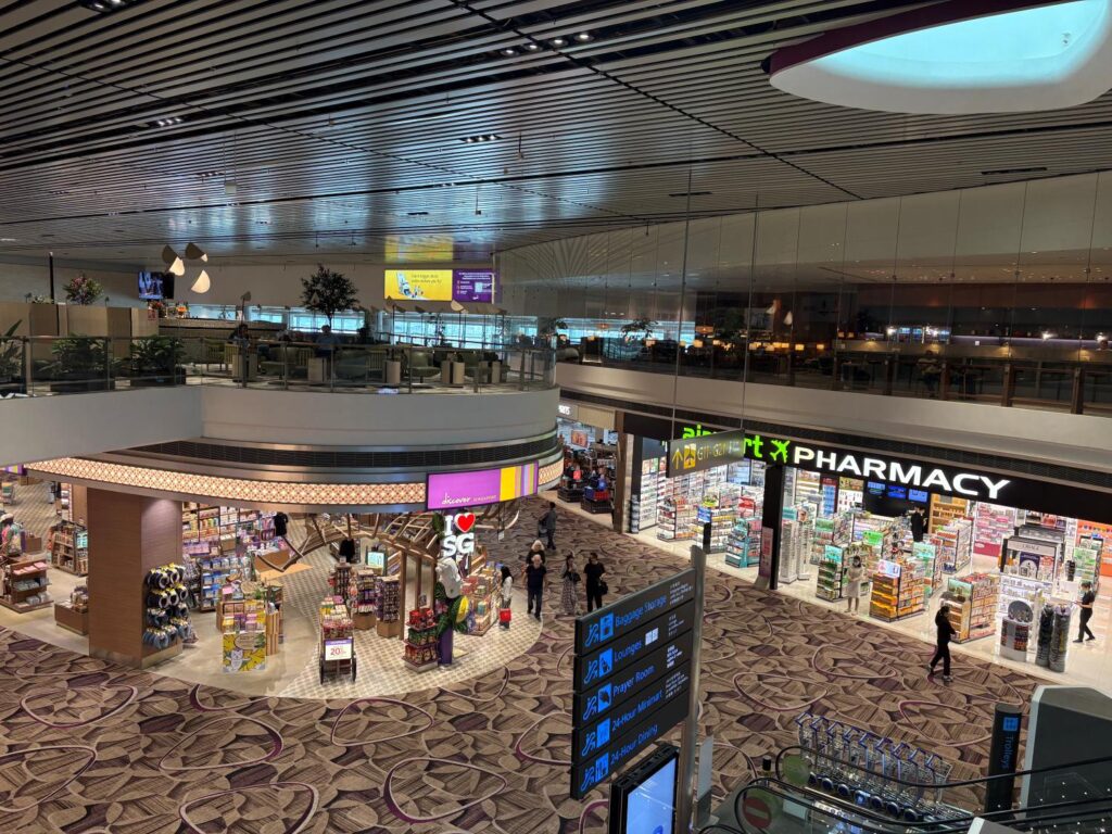 A wide shot from second storey of Changi Airport showing shops and a pharmacy