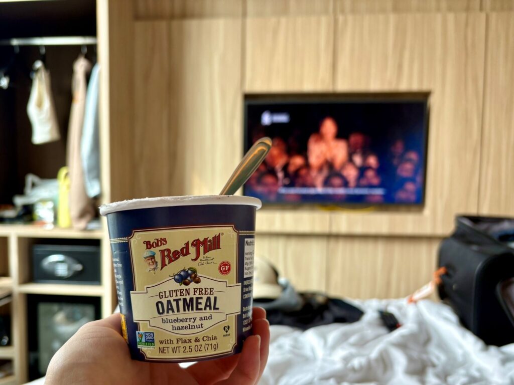 Person holding a pottle of gluten-free oats in a hotel room