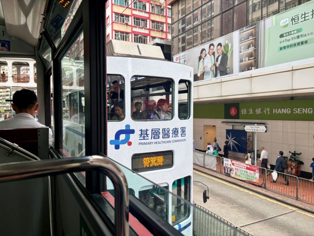 View out of a Hong Kong tram of while passing beside another Hong Kong tram