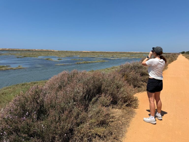 Woman on a hiking trail looking through binoculars practicing digital detox travel
