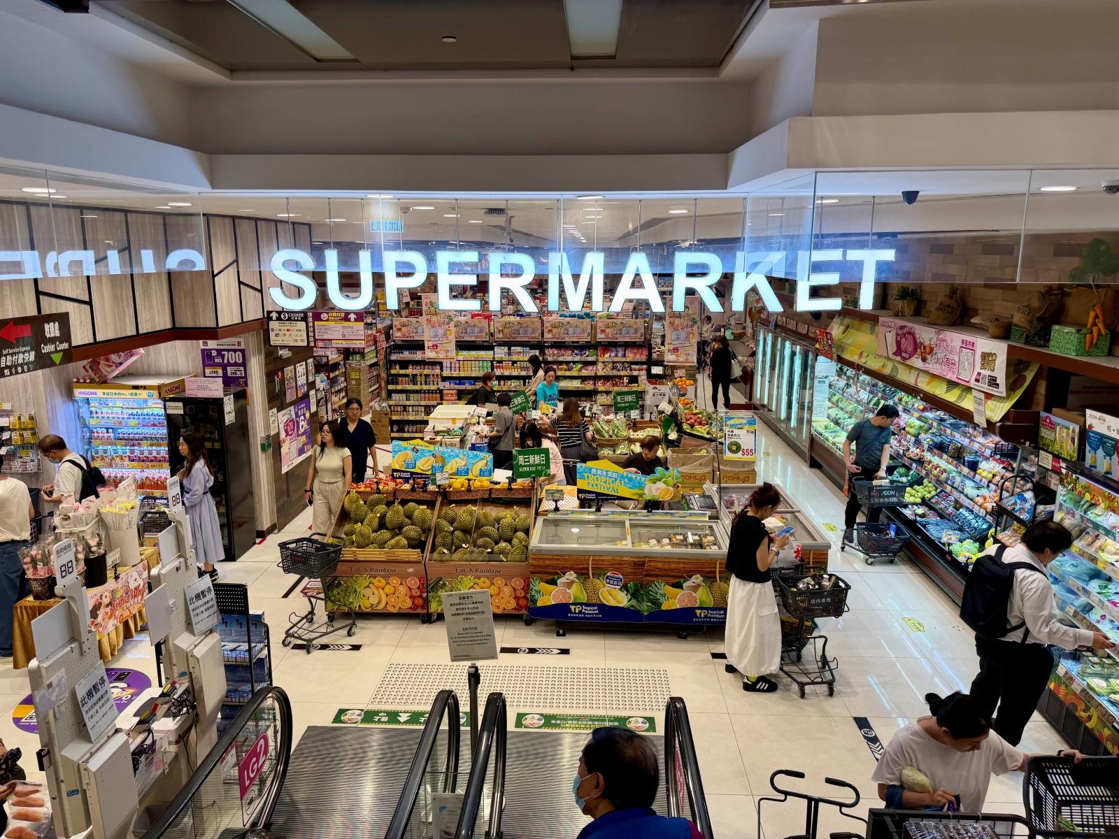 A supermarket entrance in Hong Kong with a wide variety of products and people shopping