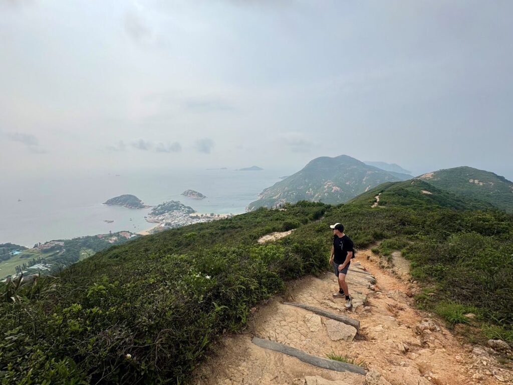 View of man looking back over the sights on the Dragon's Back hiking trail Hong Kong