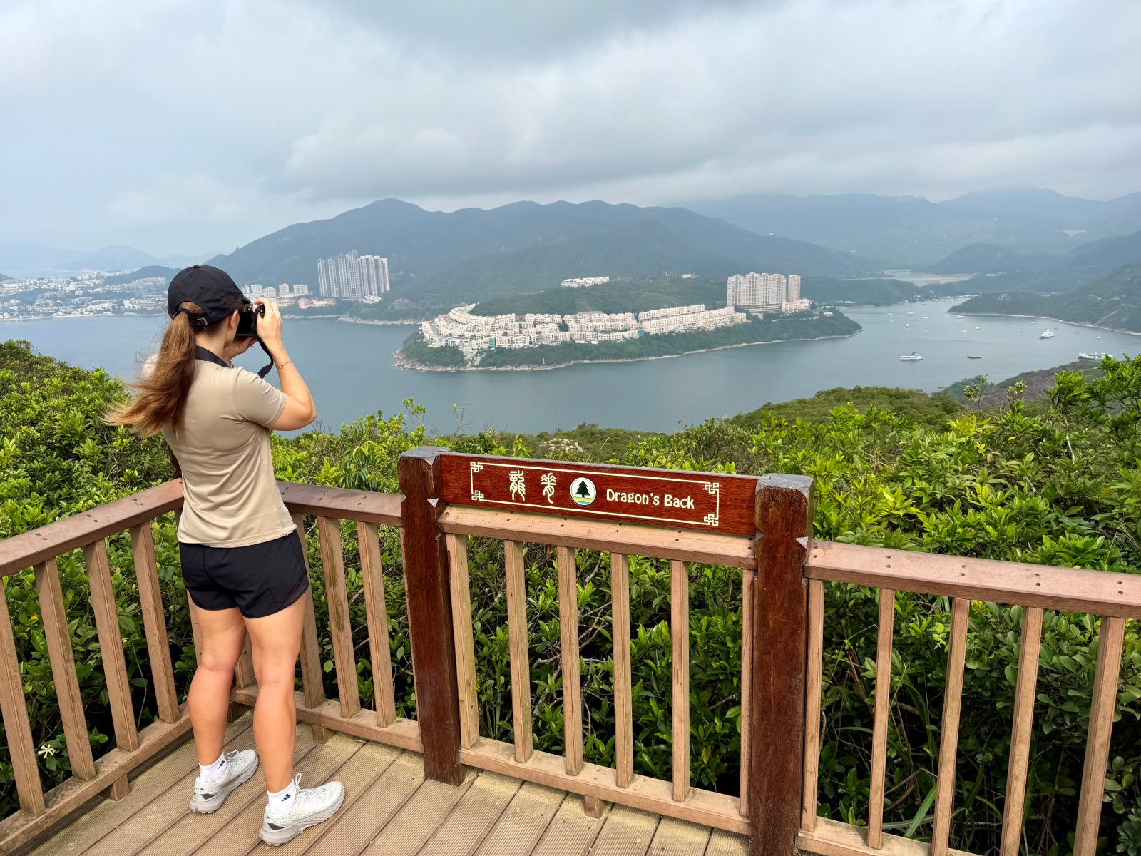 Woman taking a photo of the view while hiking Dragon's Back in Hong Kong