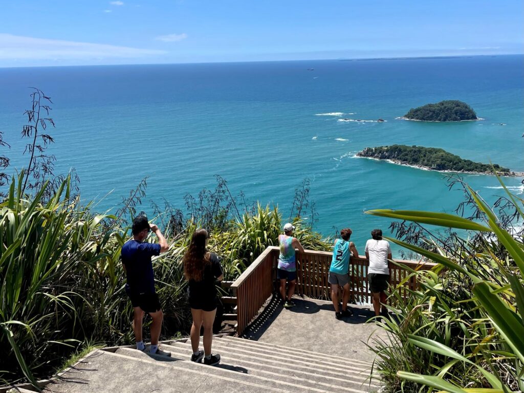 Several travellers look over the view of the ocean with no one on their phones