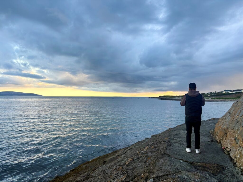 A man watching the sunset in Ireland, representing a calm-cation, taking their time to enjoy the moment