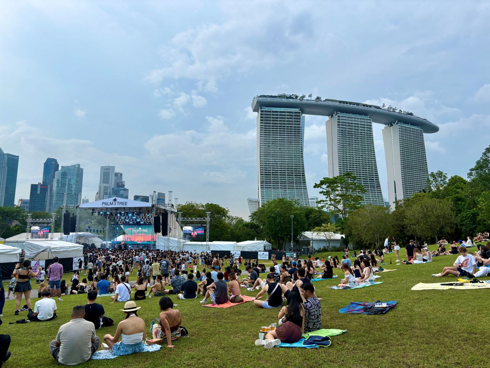 People sit down away from a crowd ar Palm Tree Music Festival, Singapore which can help with festival anxiety