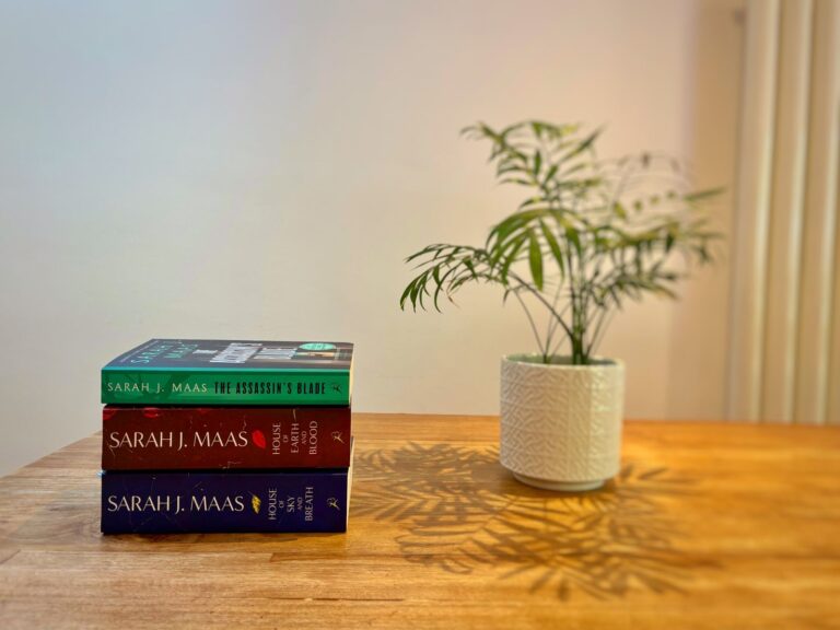 A pile of fantasy books lie on a table, a stack ready to be read on holiday